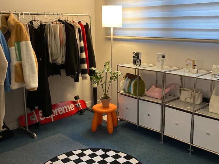 ブルーのカーペットと白い壁、クローゼット用ハンガーとフロアランプが配置された印象的なドレッシングルーム