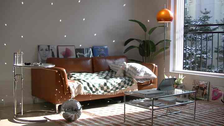 ベージュ調のリビング、ブラウンレザーのソファとメタルフレームのテーブルが配置された自然なミッドセンチュリーモダンの印象的な空間