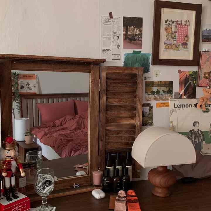 ブラウンの木製化粧台とピンクのベッドリネンが映る、落ち着いた雰囲気の寝室