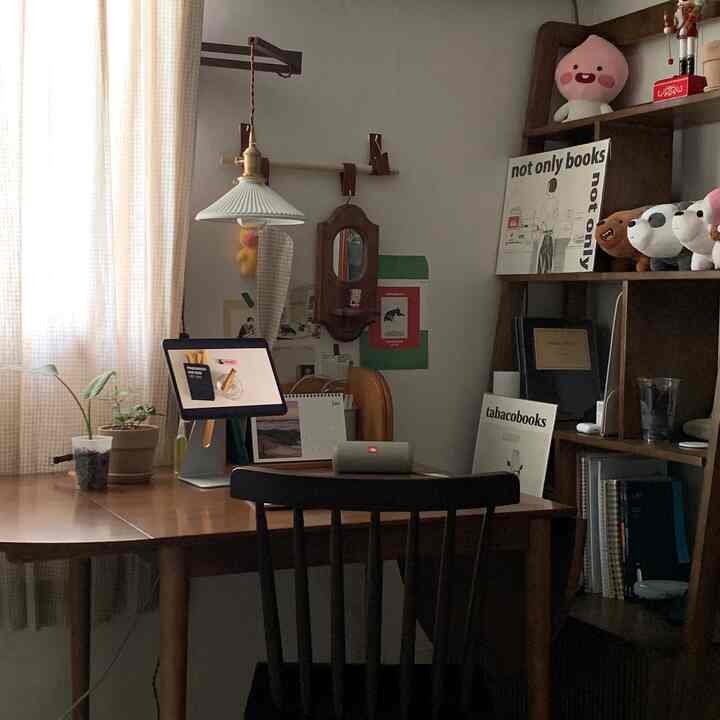 ナチュラルトーンのダイニングルーム、木製のダイニングテーブルと椅子、オートミールカラーのカーテン、壁に配置された棚が調和した雰囲気のあるインテリア