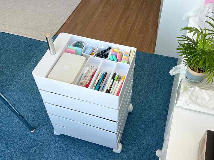 白と青のトーンのオフィス空間、白い組立式引き出し整理箱に文房具が整然と配置された実用的な空間