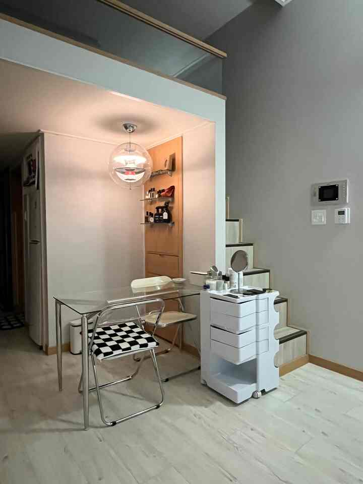 白と木目調が調和する小さなダイニングルーム、透明なガラスのダイニングテーブルと折りたたみ椅子、ロフトへ続く階段が印象的なすっきりとした空間