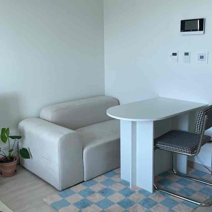 柔らかなベージュとホワイトの色調のリビング、ソファと半楕円形のダイニングテーブルが配置されたモダンなインテリア