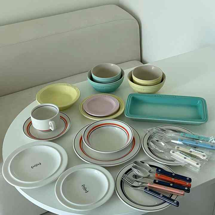 やさしいパステルとナチュラルカラーのダイニング、さまざまなボウルとコーヒーカップが配置されたシンプルな空間