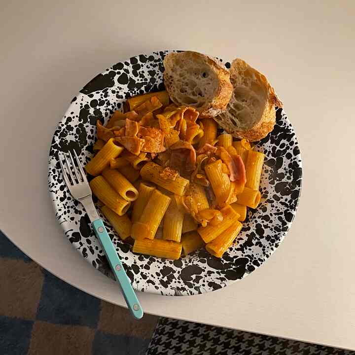 ホワイトのテーブルに黒い斑点模様の皿、パスタとパンが置かれた一人暮らしのホームカフェ風な寝室のインテリア