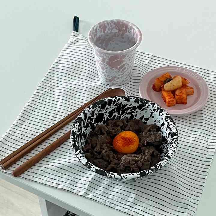 白いテーブルの上にクラウキャニオンの黒白マーブルのボウルとピンクの皿、木製箸が配置されたシンプルなおうちカフェのテーブルセット