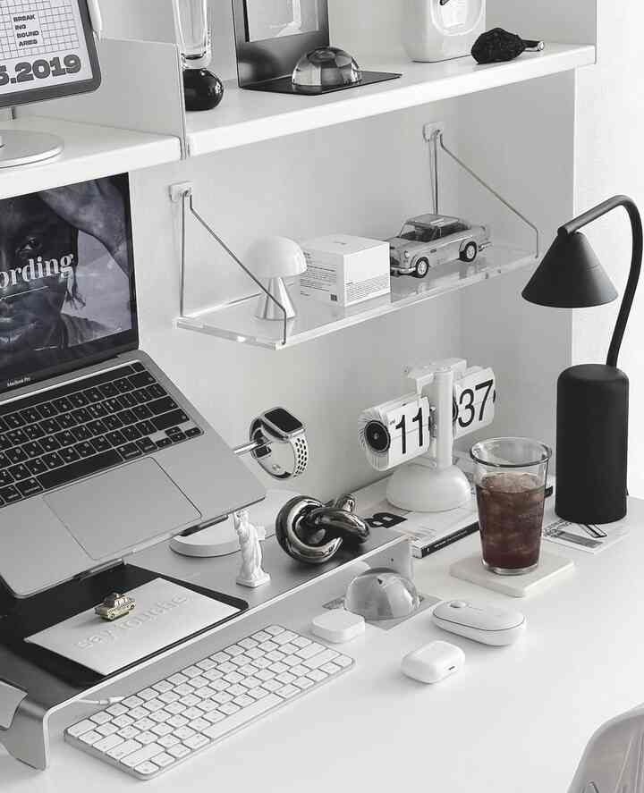 白と黒の配色のホームオフィス、ノートパソコンスタンドとテーブルランプが置かれた整然としたデスクスペース