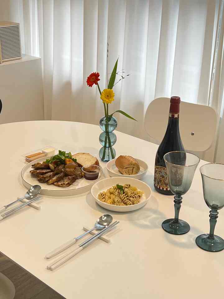 白を基調としたモダンなダイニングルーム、テーブルにワインと食事が配置された雰囲気のあるインテリア