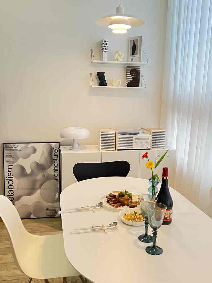 白と木目調が調和したモダンなダイニング、ダイニングテーブルとチェア、ワインとポスターが配置された雰囲気あるインテリア