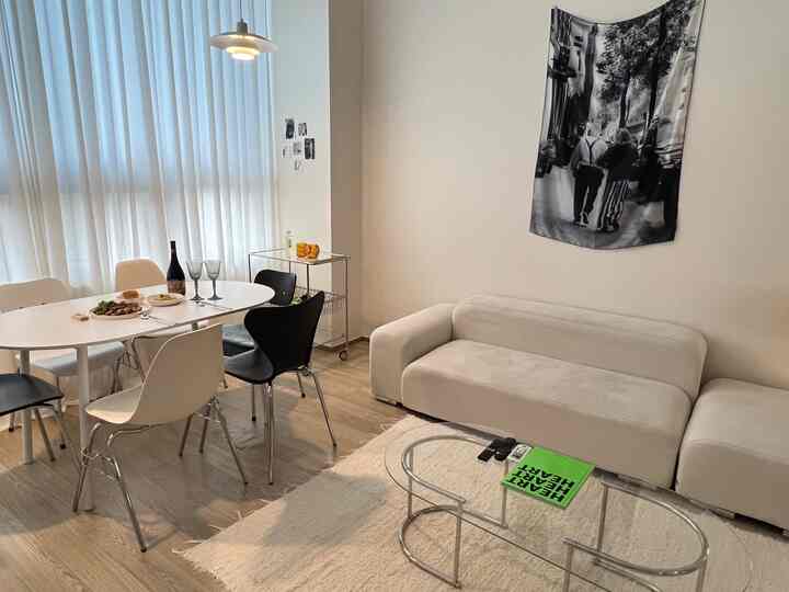 明るいホワイトとウッドトーンが調和する4人暮らし向けのリビング兼ダイニング、モダンなソファとペンダントライトが配置された空間