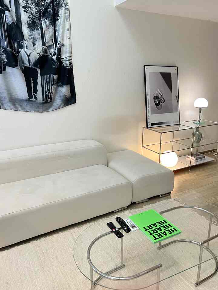 ホワイトとナチュラルカラーのリビング、シンプルなソファとガラス製コーヒーテーブルが配置された雰囲気のあるインテリア