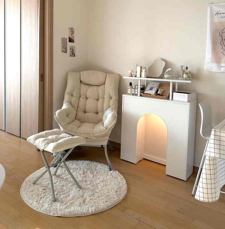 アイボリーとナチュラルカラーのワンルームリビング、快適なアームチェアとアーチ型の壁暖炉コンソールが配置された居心地の良いインテリア