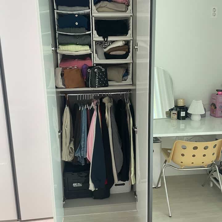 白とベージュを基調としたワンルーム、広いクローゼットと化粧台が配置された整理された収納空間