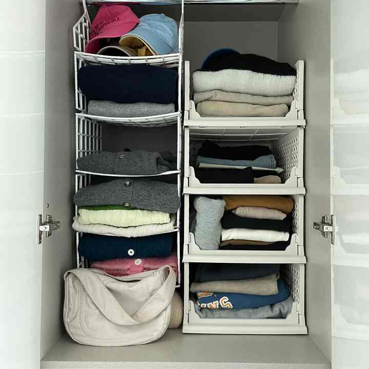 白とベージュのトーンのクローゼット内、スライディングリビングボックスと棚ハンガーに衣類が整頓された印象的な空間