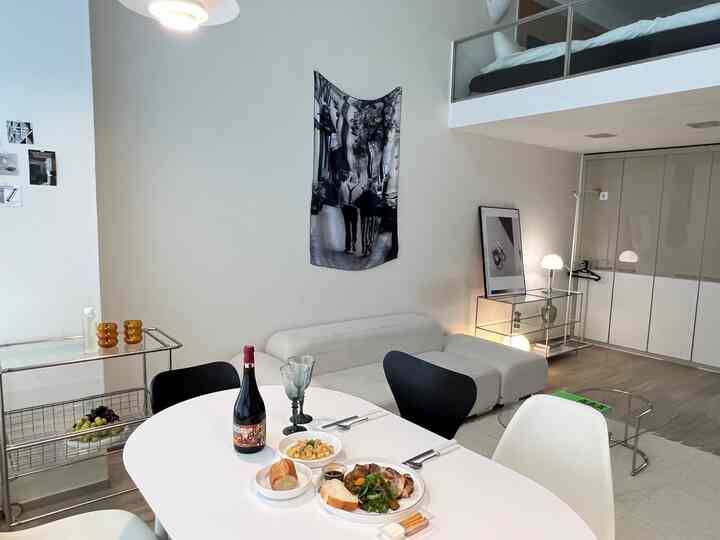 白を基調としたリビングとダイニングスペース、食卓には食事とワインが置かれ、落ち着いたホームカフェの雰囲気のあるインテリア