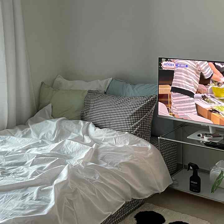 清潔感のある白を基調とした寝室、アクセントピローとテレビ台が配置された落ち着いた空間