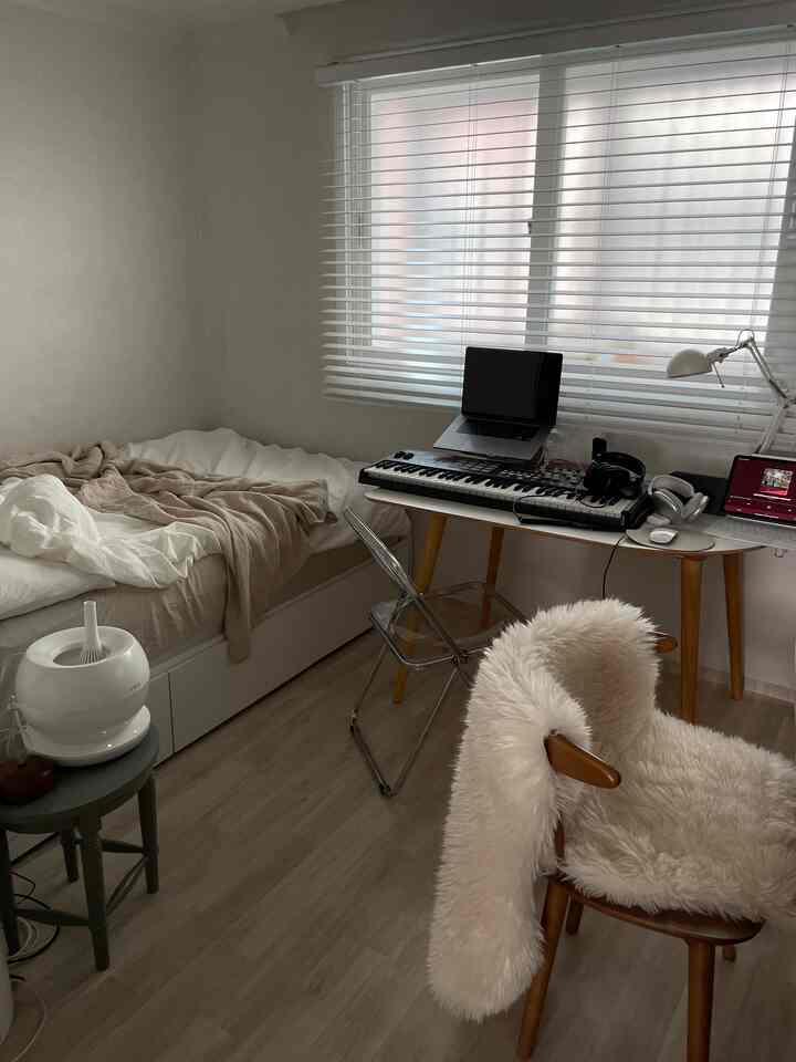 ホワイトとベージュのトーンの寝室、ベッドとデスクが並んで配置されたシンプルで自然な雰囲気のインテリア