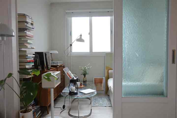 白と茶色の色調の北欧風リビング、ガラステーブルや照明、書籍が配置された雰囲気のあるナチュラルモダンな空間