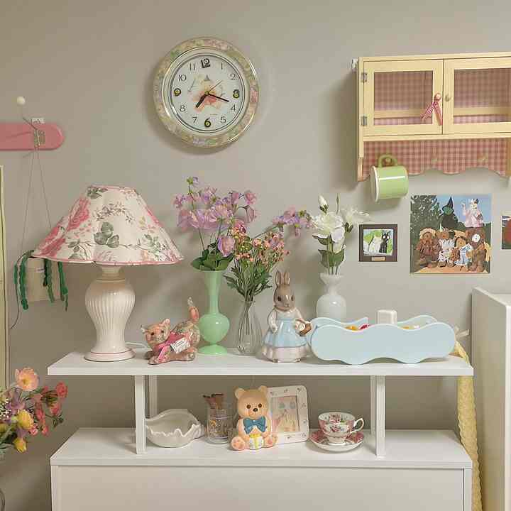 暖かいベージュ色の壁と白いコンソールテーブルの上に花瓶とヴィンテージのオブジェが並ぶ魅力的なヴィンテージインテリア空間