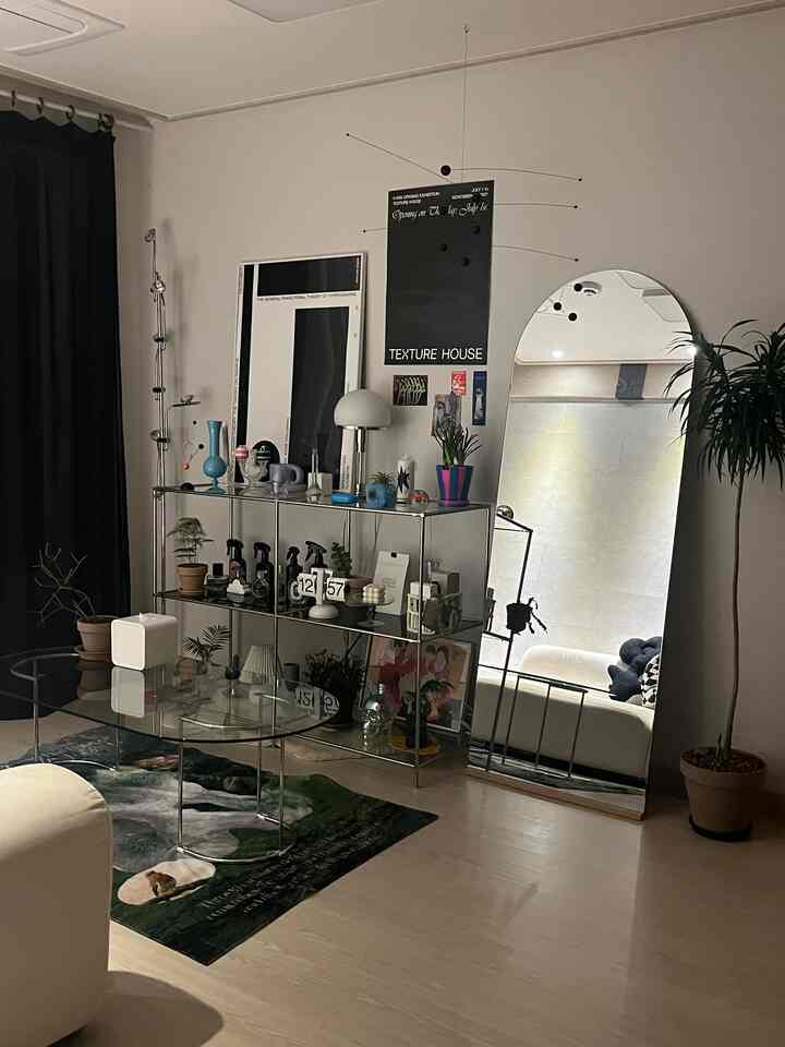 ホワイトとブラックの色調のリビング、ガラステーブルや多様なインテリア小物が配置され、ナチュラルモダンな雰囲気のあるインテリア