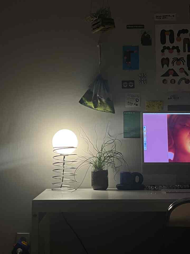 白を基調としたホームオフィス、机の上にテーブルランプと植物が置かれたシンプルなインテリア