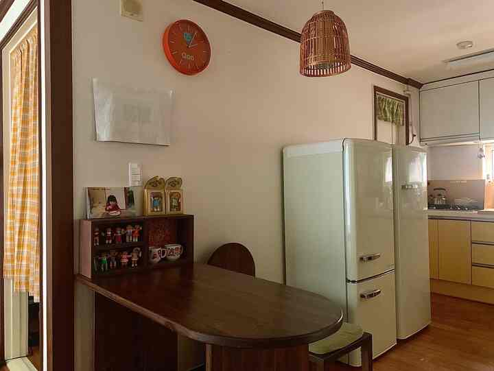 バター色と木目調が調和するキッチンとダイニングスペース、レトロな冷蔵庫が配置された落ち着いた雰囲気のインテリア