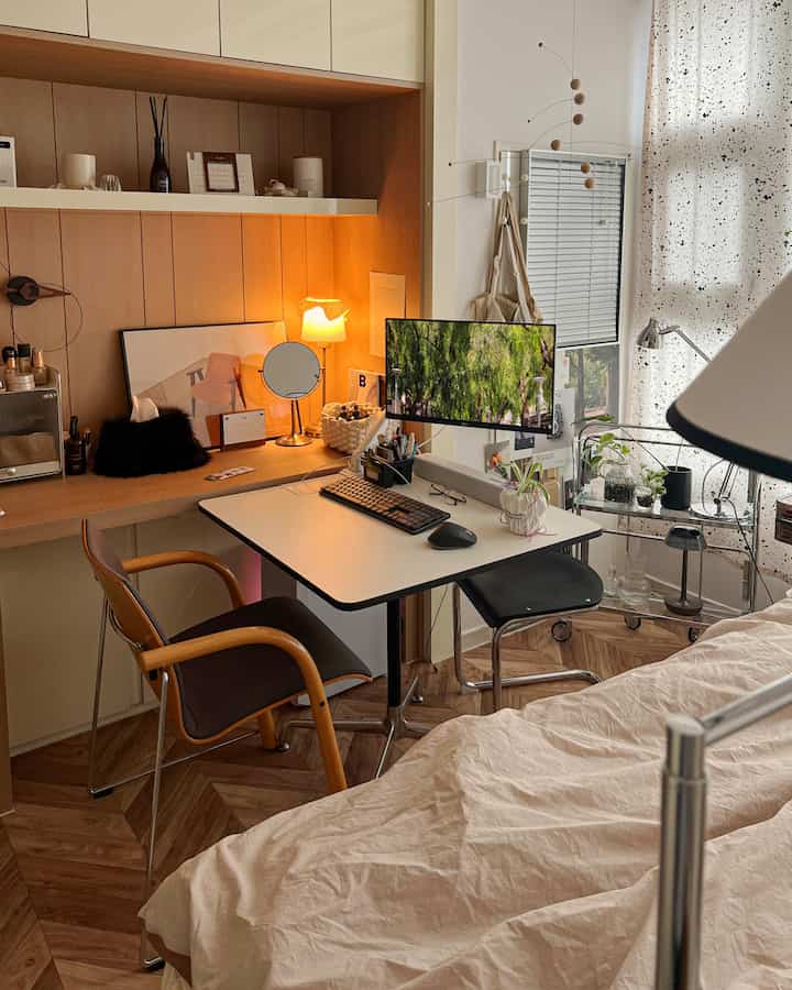 ホワイトと木目調が調和したワンルーム寝室兼ホームオフィス空間、ビルトイン家具前に広く配置されたデスクと椅子を特徴とする