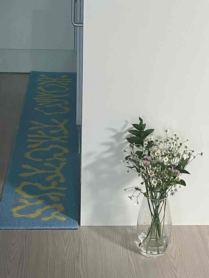 白と木目調が調和した空間、床に置かれた花瓶とラグが映えるナチュラルなインテリア