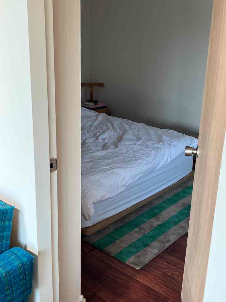 白い壁とベッド、木目調の家具が配されたシンプルな寝室の雰囲気のあるインテリア