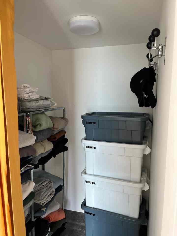 白とグレーの色調のウォークインクローゼット、ステンレスの棚と大容量のリビングボックスが整然と配置された収納スペース