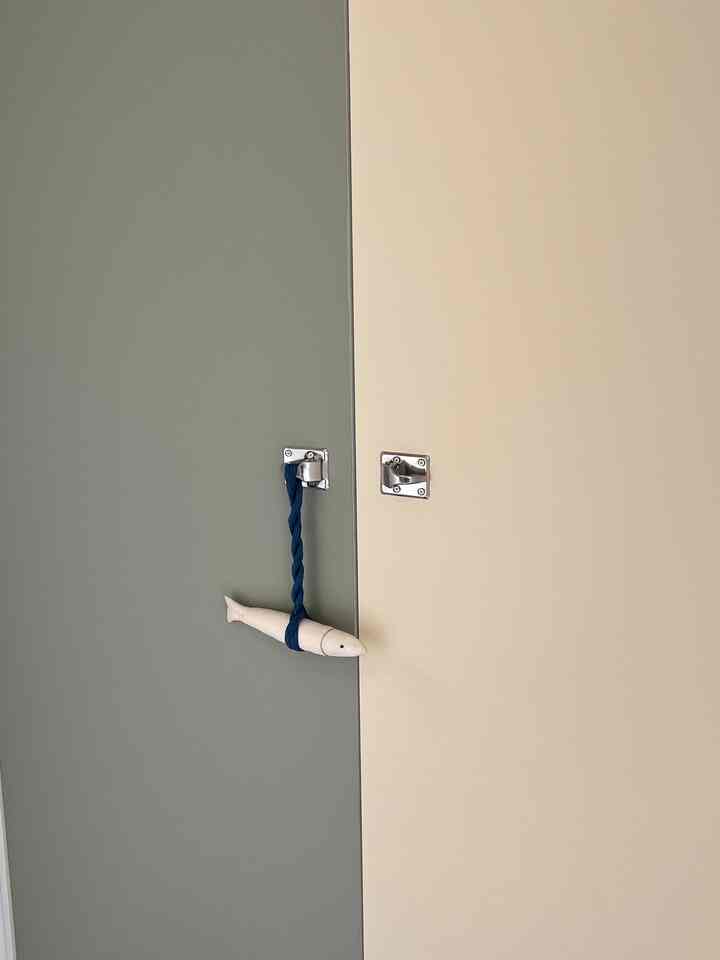 淡い緑とベージュ色の扉が配置された玄関のシューズラック、スウェーデンベスラーグの取っ手が特徴的なモダンな空間