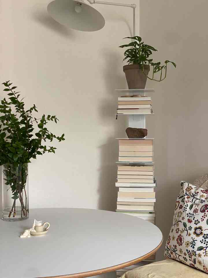 白とウッドトーンが調和するリビング、丸テーブルと植物が配置されたシンプルでモダンな印象的な空間