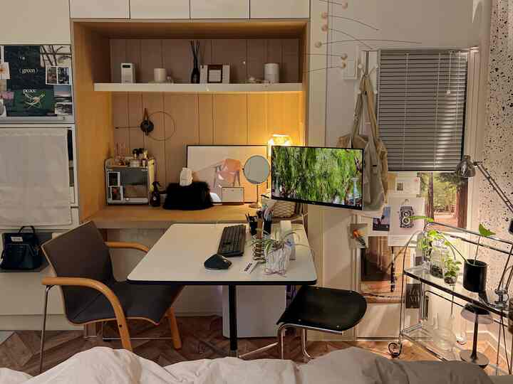 ナチュラルな木目調とホワイトが調和したワンルームのホームオフィス、モビールと植物がアクセントの落ち着いた作業空間