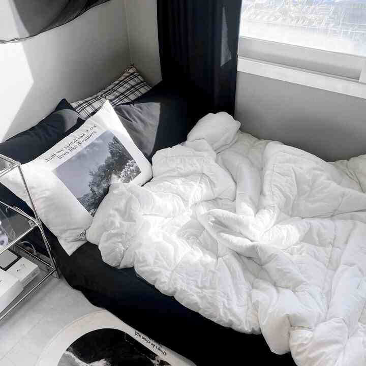 モノトーンの黒と白の寝室、黒の遮光カーテンと白い寝具、枕が配置されたモダンでシンプルな雰囲気のあるインテリア