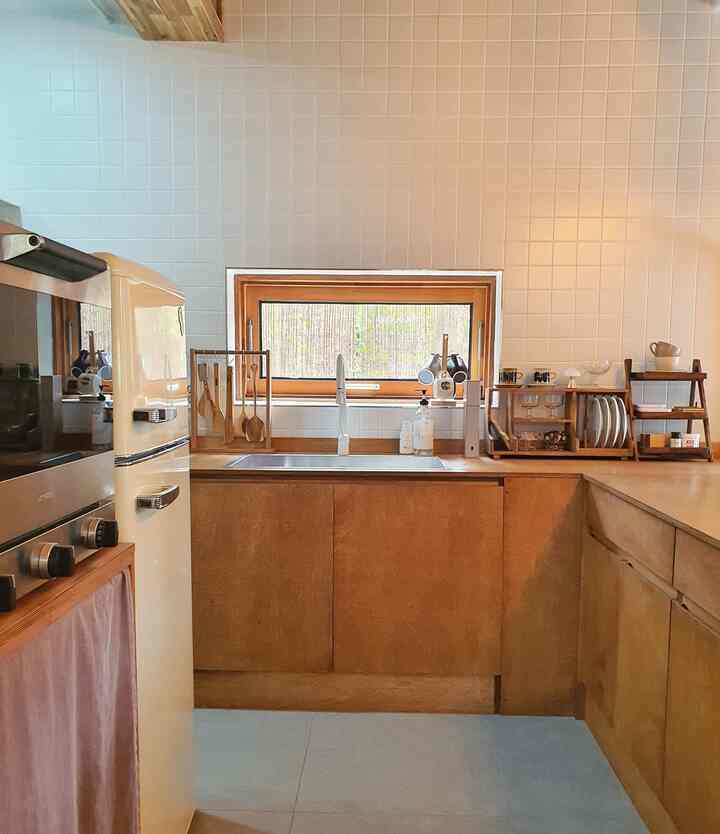 ナチュラルカラーのキッチン、木製調理器具スタンドとミニレトロ冷蔵庫が配置された雰囲気のあるインテリア