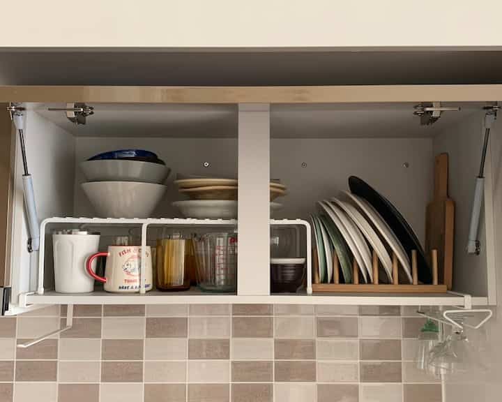 ナチュラルな色調のキッチンキャビネット、整然と収納された皿やボウル、ガラスが配置された雰囲気のあるインテリア