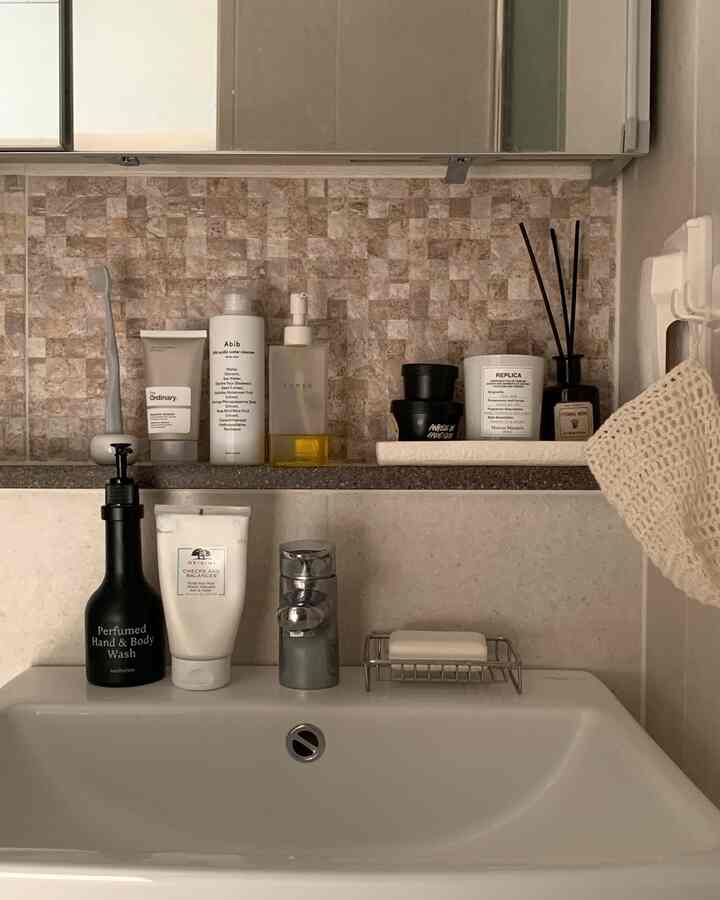 ナチュラルな色調のトイレ洗面台、陶器のトレイにソープとキャンドルがおかれた清潔感のあるインテリア