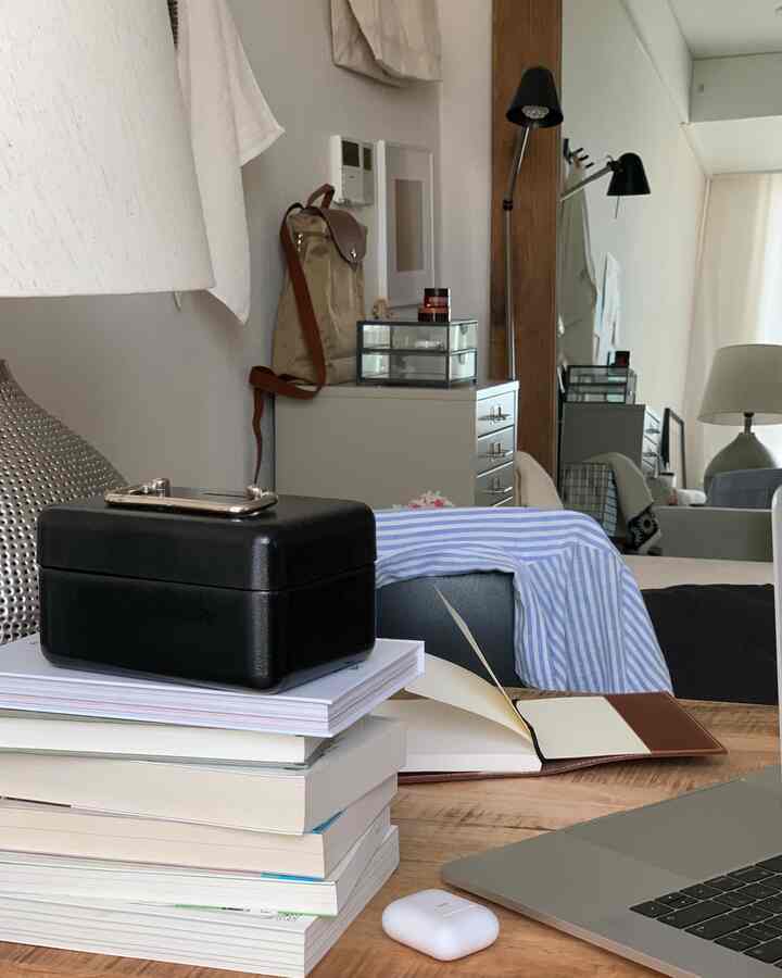 白と茶色の落ち着いたトーンのホームオフィス、机の上に本とノートパソコンが置かれ、在宅勤務に適した快適な作業環境が広がるインテリア