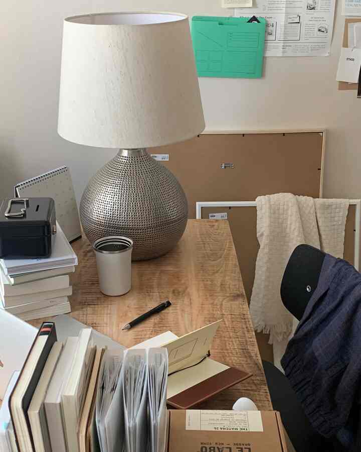 木目調のデスクとシルバーベースのテーブルランプが配置された自然な雰囲気の書斎