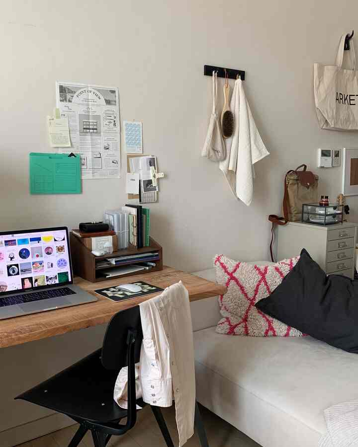 白い壁と木目調のデスクが配置されたホームオフィス、ソファとクッションが調和する雰囲気のある空間