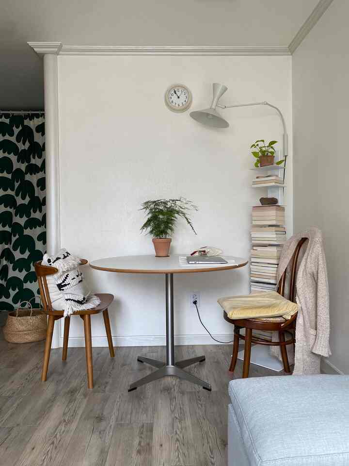 白と木目調が調和した二人用ダイニング、壁照明と観葉植物が配置された落ち着いた空間