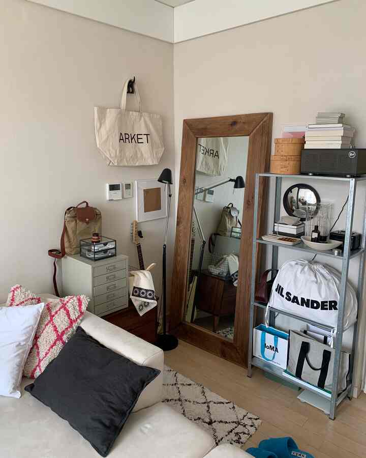 ホワイトと木目調が調和する一人暮らしのリビング、木製の大きな全身鏡と棚が配置された自然な雰囲気のあるインテリア