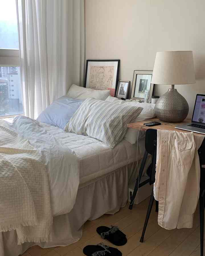 白とナチュラルトーンの寝室、ベッドとデスクが配置された居心地の良い空間