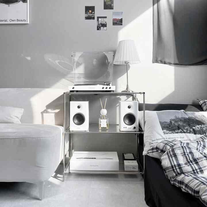 モノトーンのブラックとホワイトの寝室、ナイトテーブルにターンテーブルとスピーカーが配置されたモダンでシンプルな雰囲気のインテリア