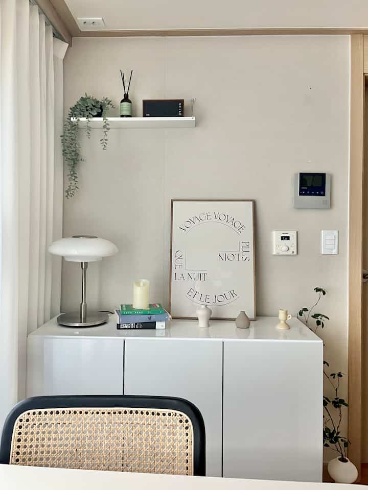 ホワイトとナチュラルトーンのダイニングルーム、シンプルに配置されたモダンなテーブルランプとポスターがある洗練されたインテリア