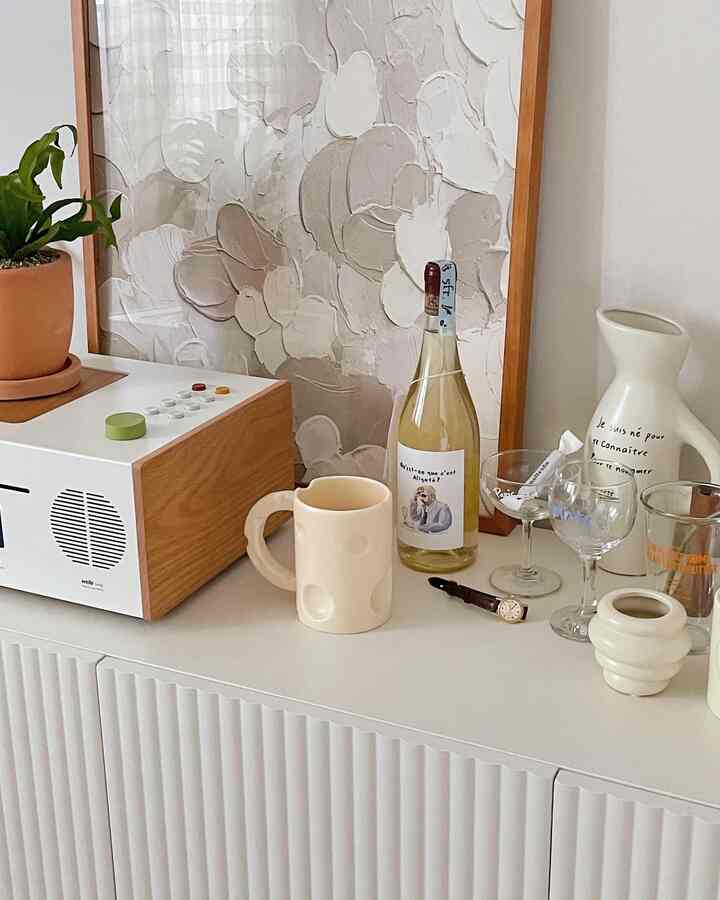 ナチュラルな木目調と白を基調としたリビングの収納キャビネットの上にオブジェが並ぶ、温かく洗練されたインテリア