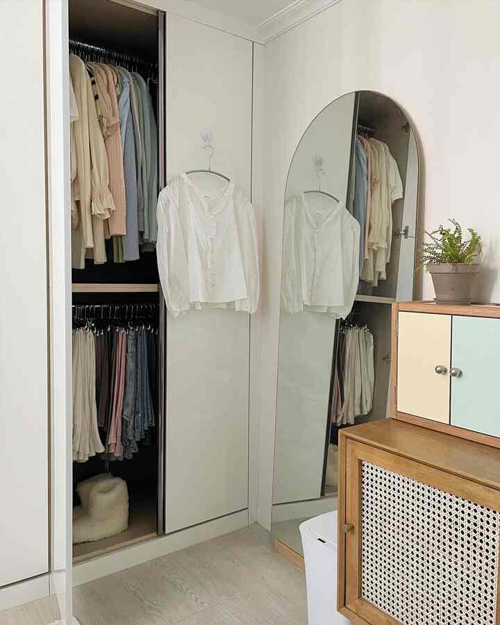 ホワイトとウッドトーンが調和した寝室の収納スペース、クローゼット、全身鏡、キャビネットが配置された自然で整った雰囲気のインテリア