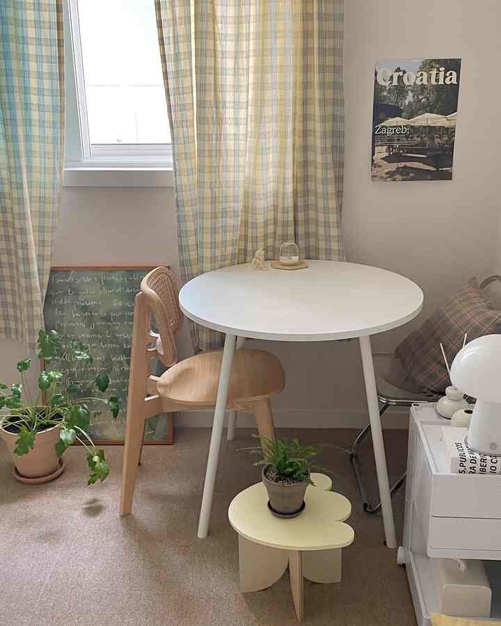 ベージュ色調のリビング、丸い白いテーブルとナチュラルウッドの椅子、植物が配置された雰囲気のあるインテリア