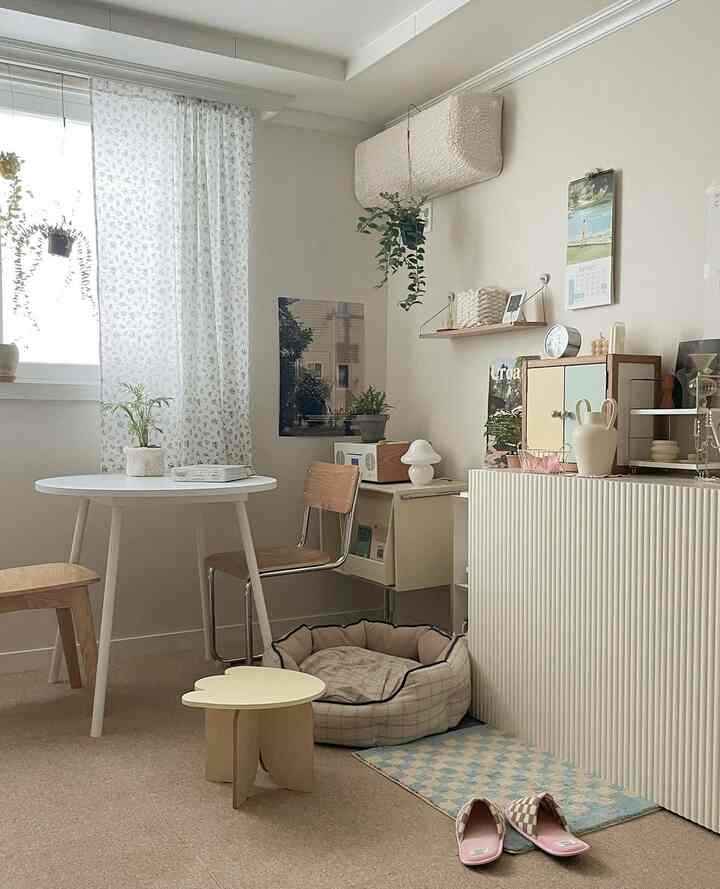 柔らかなベージュとナチュラルウッドトーンのリビング、丸テーブルとクッションが調和する居心地の良いシンプルな空間