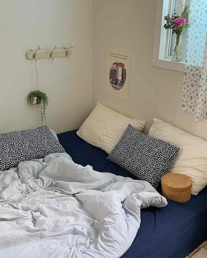 ネイビーのマットレスカバーと白い寝具が調和したシンプルでナチュラルな雰囲気の寝室